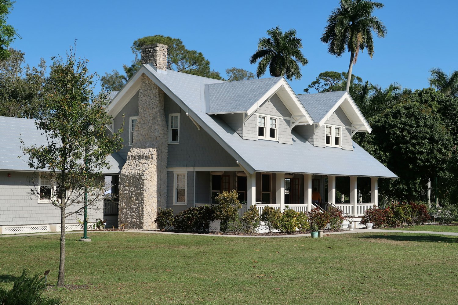 A classic grey weatherboard home with stone chimney and verandah, freshly painted