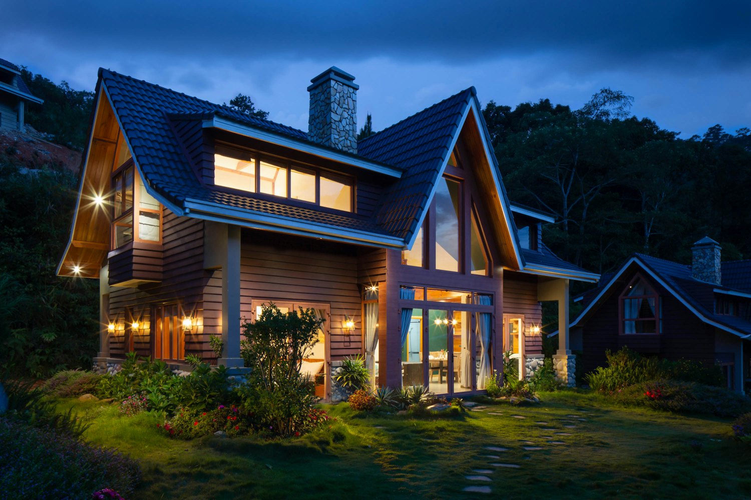 A freshly painted two-storey timber-clad home lit warmly at dusk