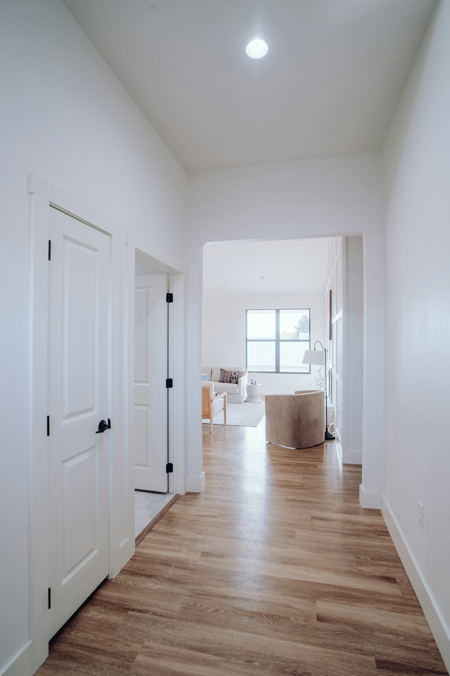 A bright white painted hallway with crisp doors and trim leading to a living area