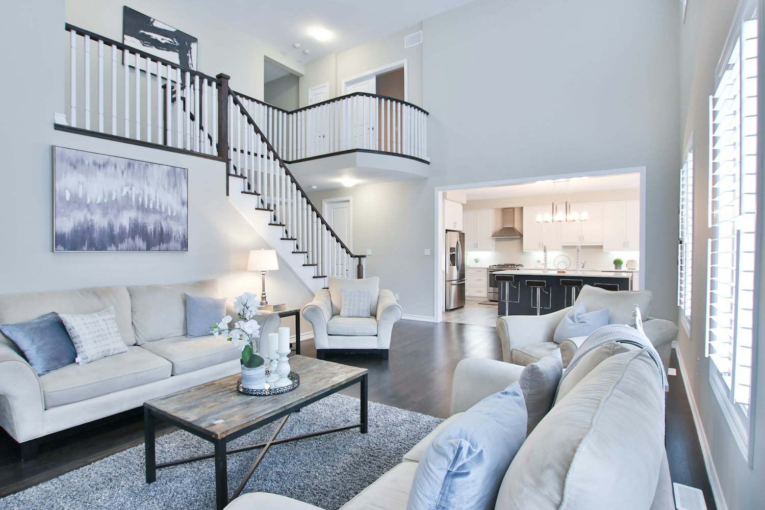 A freshly painted double-height living room with staircase and crisp white trim in soft neutral tones