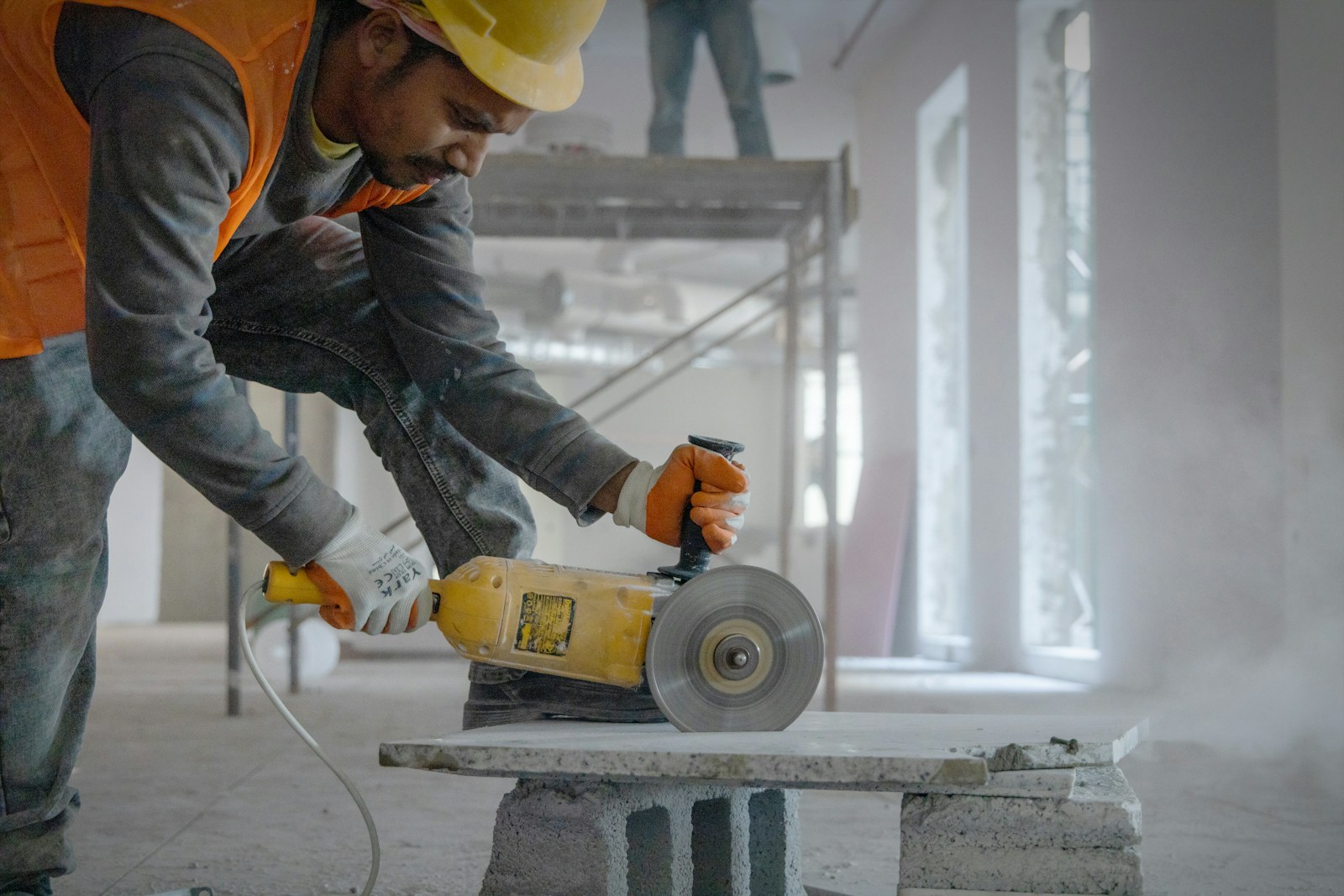A tradesperson diamond-grinding a concrete edge, dust haze catching the light.