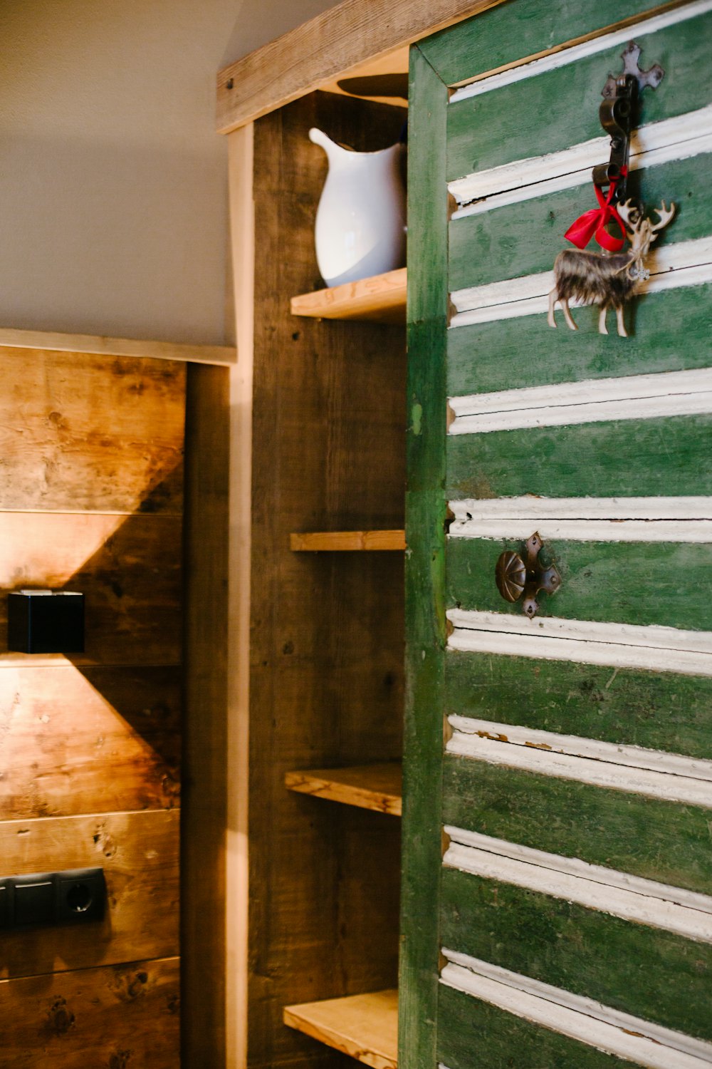 Custom built-in shelving in reclaimed timber with a heritage green cabinet door