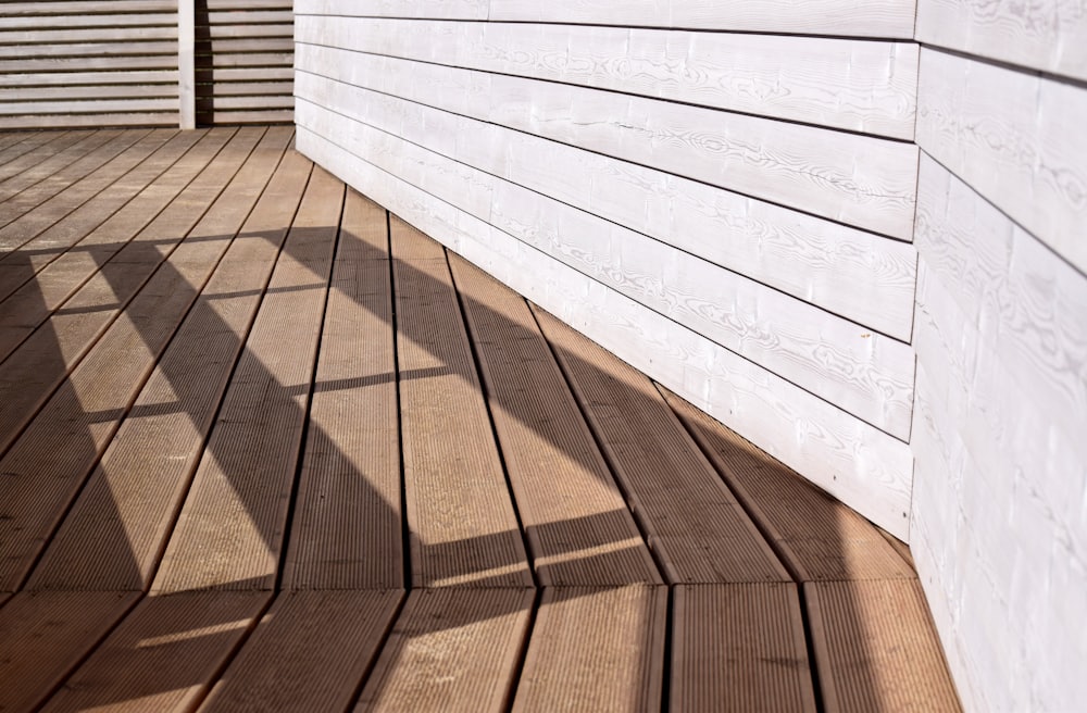 Newly laid hardwood decking boards in afternoon sun beside white timber cladding