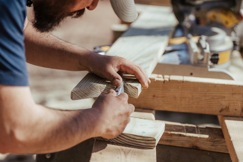 Hands chiselling a clean joint into a length of timber on a workbench outdoors