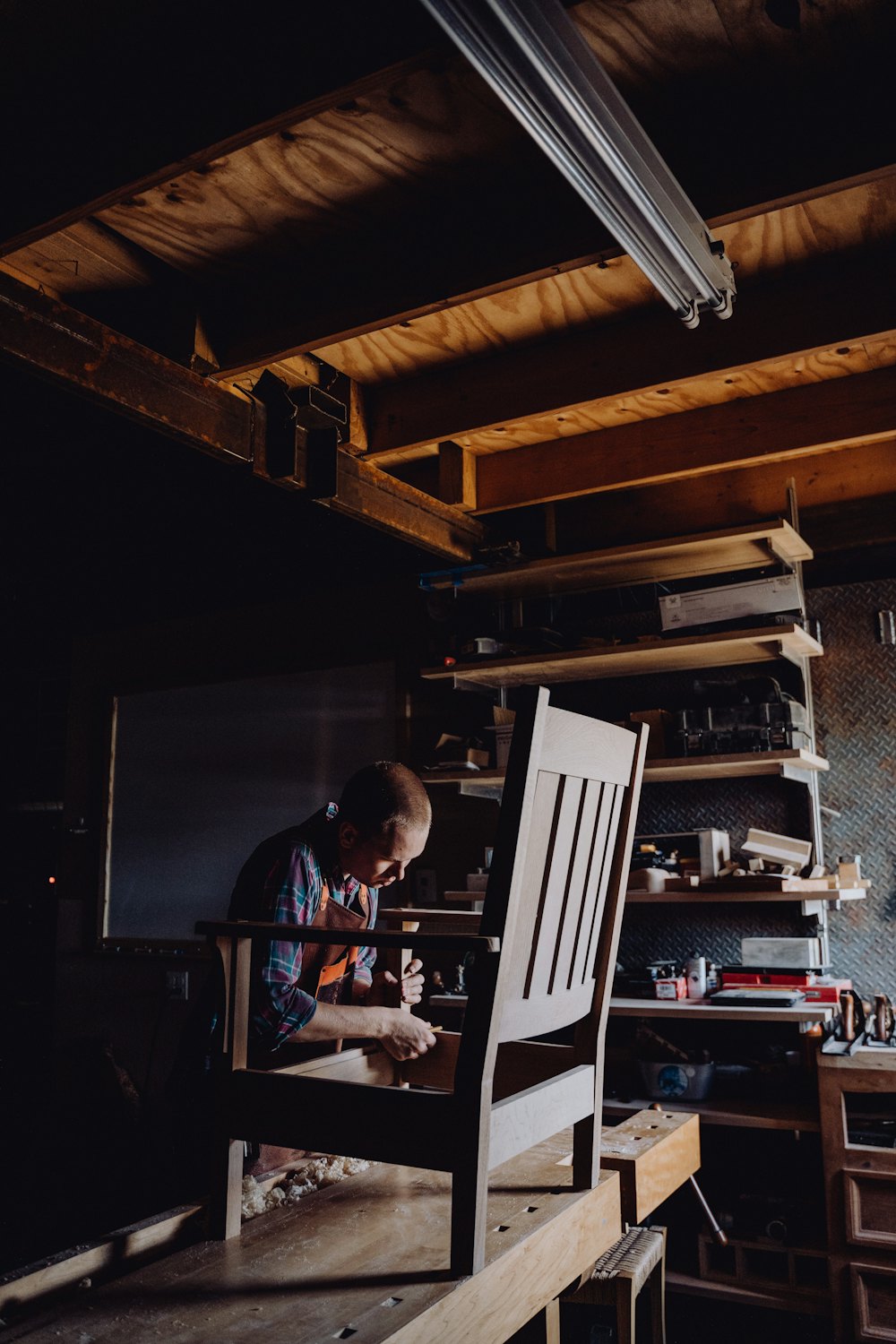A solid timber chair being hand-finished in a warmly lit workshop